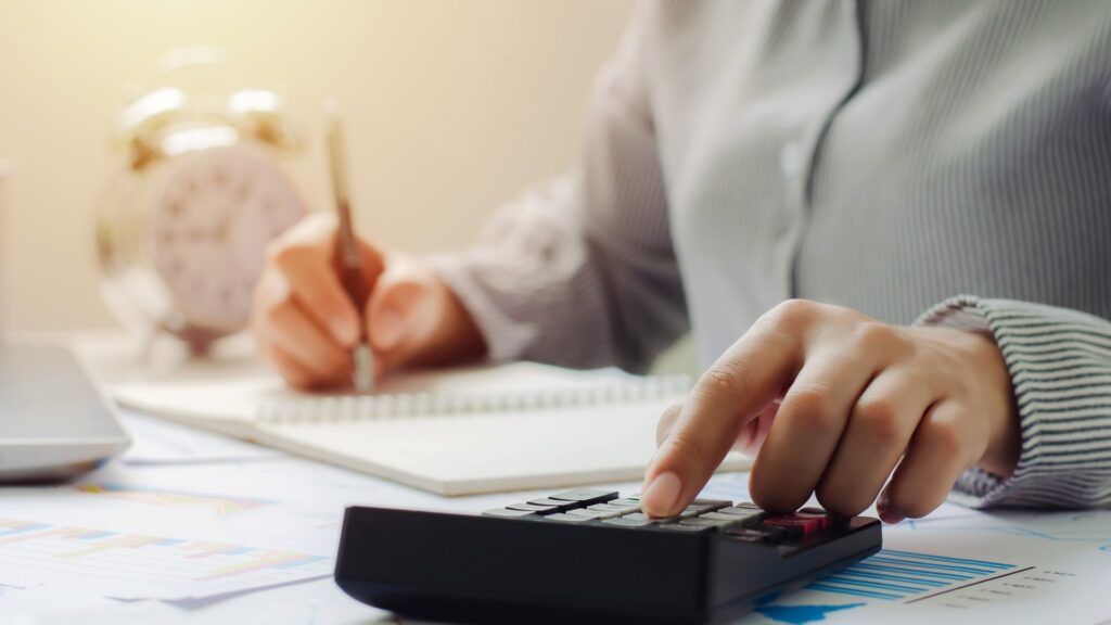 Cloud Based Tax Software — calculating figures with a calculator and paperwork